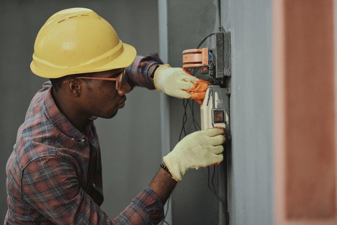 Electrician installing wiring while wearing a yellow hard hat