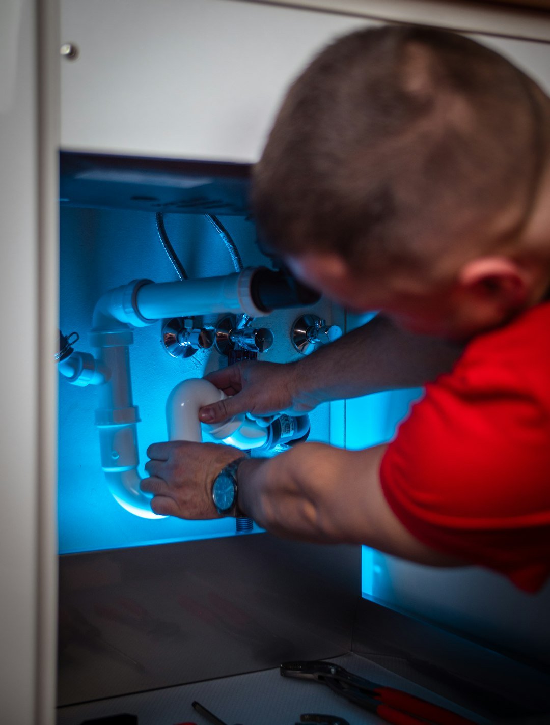 Local service worker repairing a pipe as part of a home service business