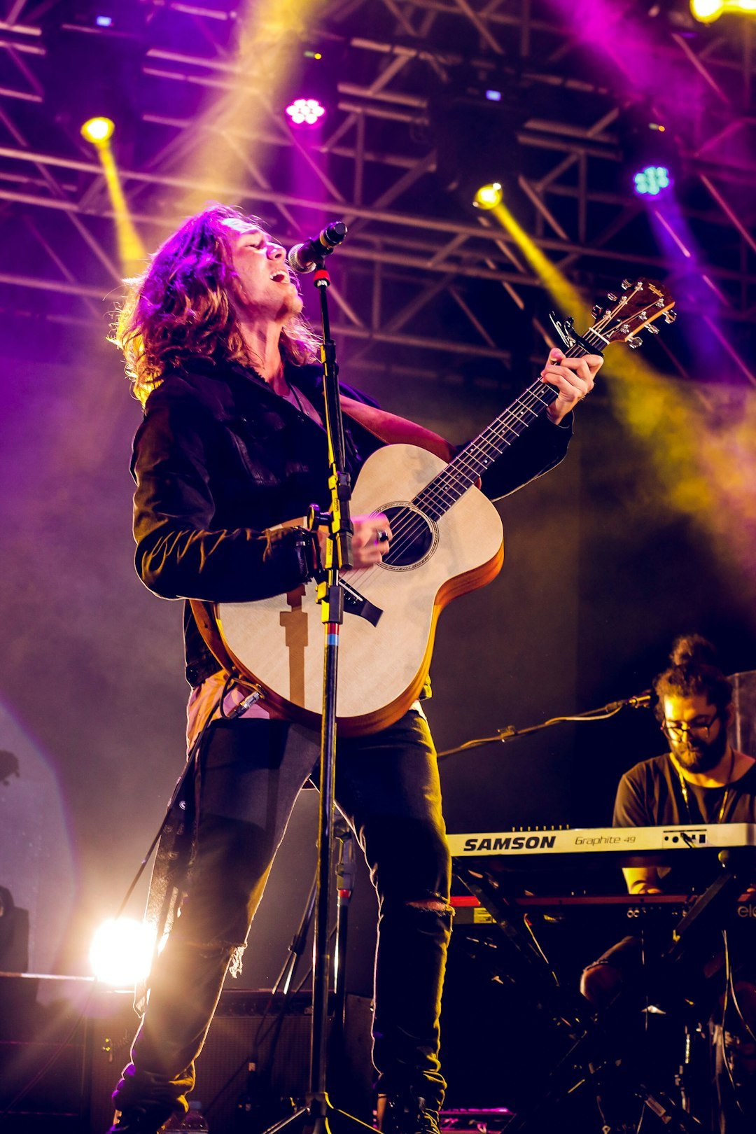 Musician singing and playing guitar on stage during a live performance
