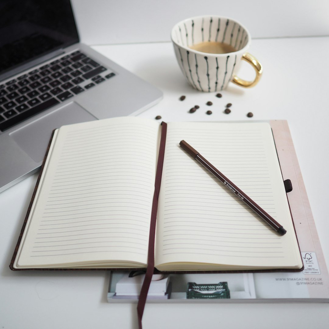 Notebook beside a laptop, used for planning blog content