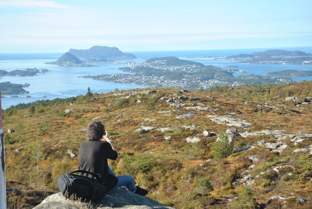 Traveler sitting on a rocky hill overlooking a coastal town